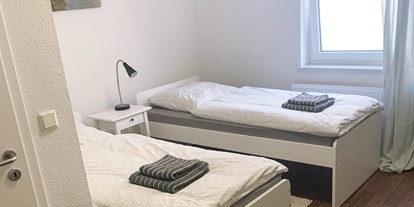 Pensionen - WLAN - Ostfriesland - Doppelzimmer mit Einzelbetten, Handtücher und Bettwäsche, Nachttisch - Pension in Emden