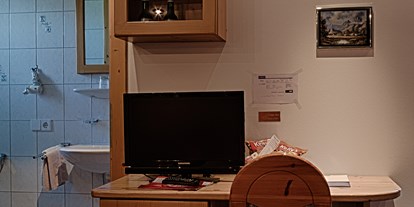 Pensionen - Seeham - Einblick ins Bad des Romantikzimmers und Blick auf den Schreibtisch, TV und Minibar unterhalb des Fernsehers.  - Gästehaus Heidi - Ihr Gästehaus mit Herz und Flair
