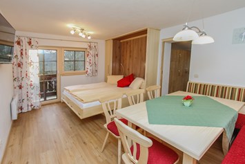 Frühstückspension: Wohnzimmer mit ausgeklapptem Doppelbett von Flexinno - Urlaubsparadies Liebmannhof