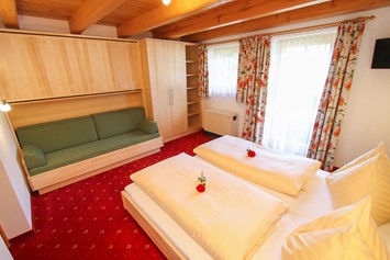 Frühstückspension: Schlafzimmer von Uromas Stüberl  zwei bis vier Betten und Sitzcouch und Fernseher mit KTV - Urlaubsparadies Liebmannhof